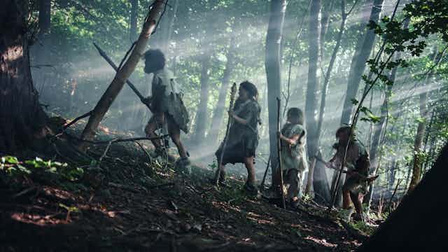Tribe of Hunter-Gatherers Wearing Animal Skin Holding Stone Tipped Tools in a forest