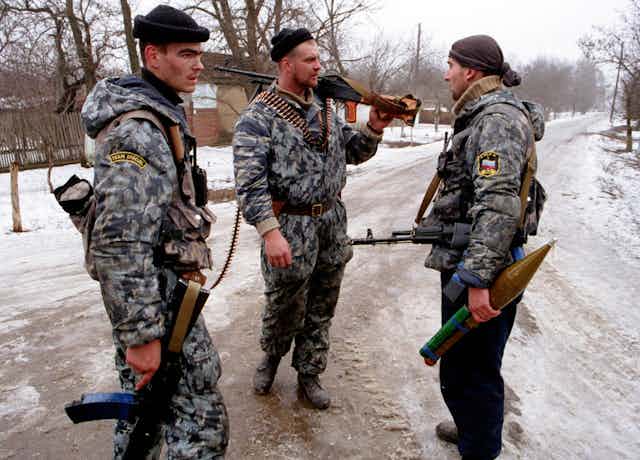 Three Russian soldiers standing in a snowy road.