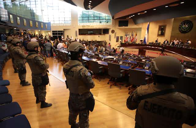 Armed soldiers stand inside a legislative chamber.