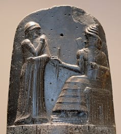 A relief showing King Hammurabi standing before a seated god of justice, Shamash.