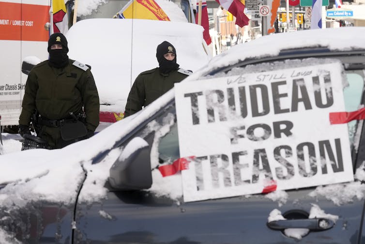 A sign on a car reading 'Trudea for treason' with two police officers in the background