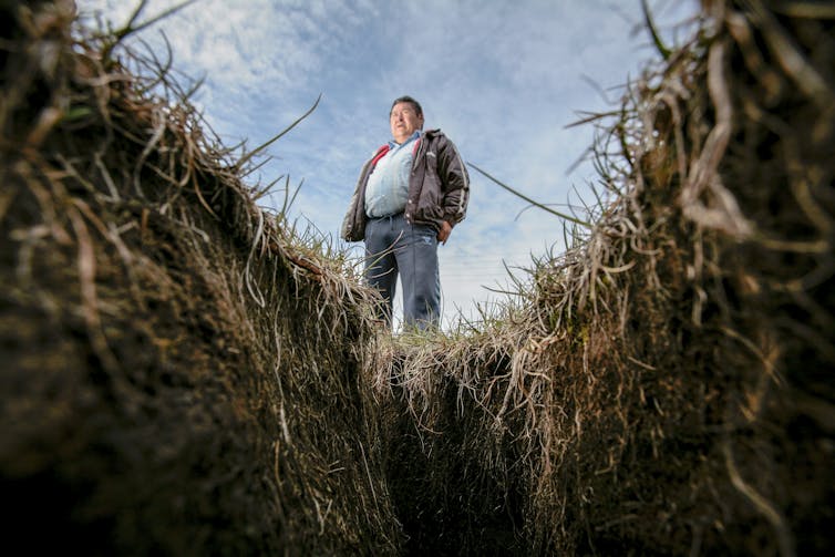 A man in Greenland stands above a large crack in the ground.