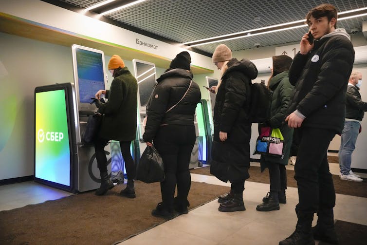People stand in line to withdraw money from an ATM in Sberbank in St. Petersburg, Russia, on Feb. 25, 2022.