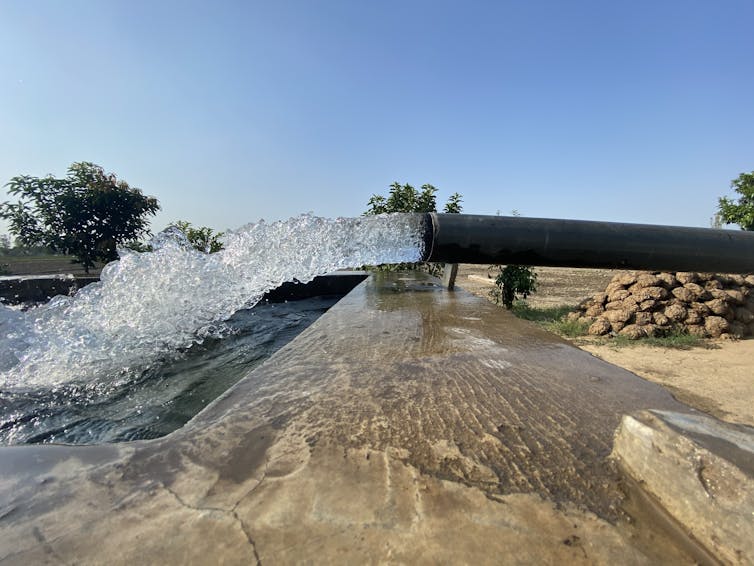 Water gushing out of a wide pipe into a reservoir.