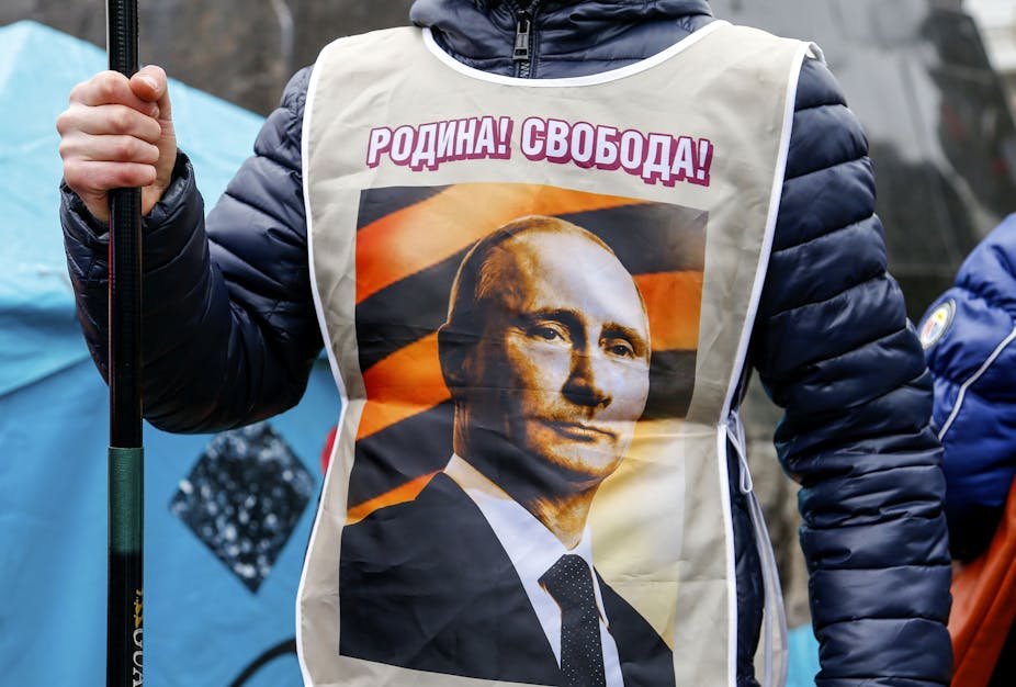 A person wears a vest with a photo of Vladimir Putin.