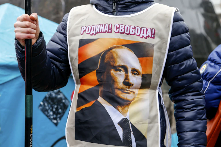 A person wears a vest with a photo of Vladimir Putin.