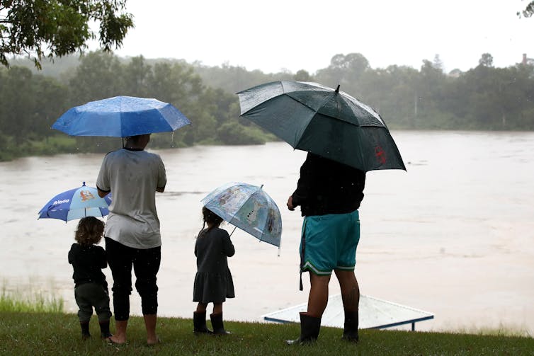 Two parents and two children watch rising floodwaters