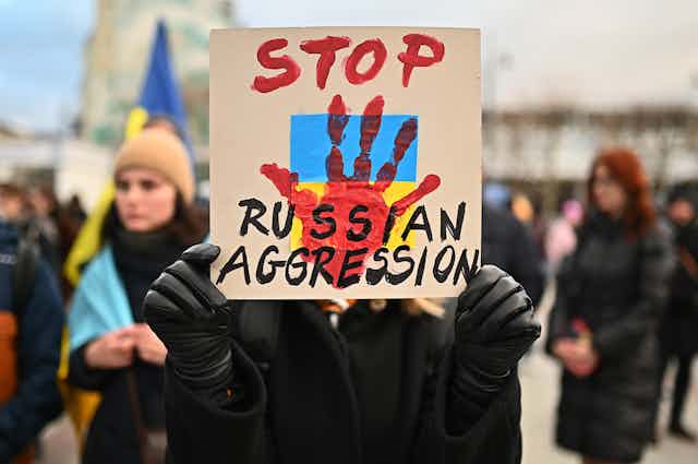 A protester in Poland holds up a nabber reading Stop Russian Aggresson with a bloody handprint