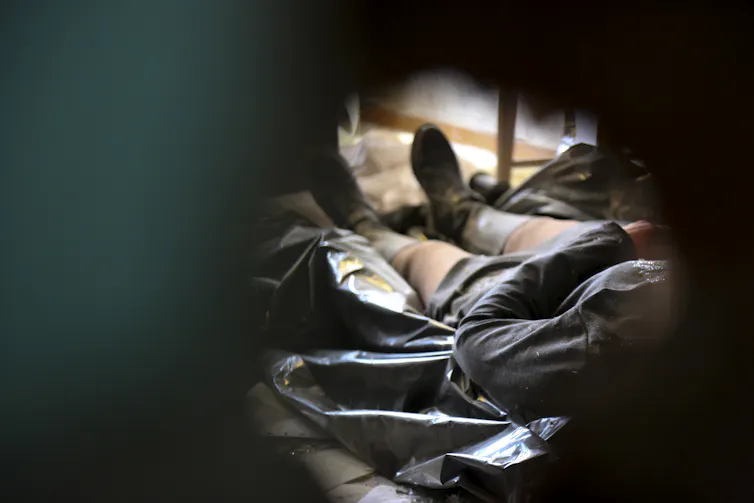 A dead body is seen through a hole.