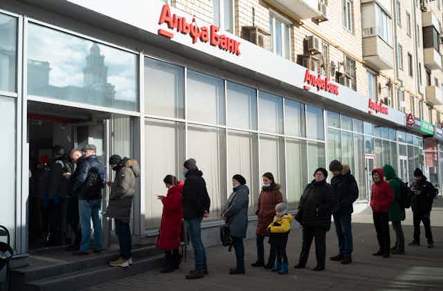 People stand in line to withdraw money from an ATM of Alfa Bank in Moscow, Russia.