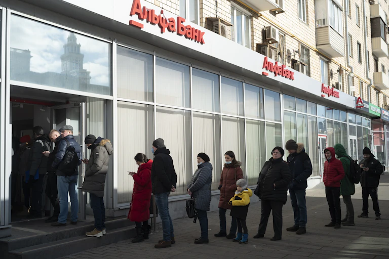 People stand in line to withdraw money from an ATM of Alfa Bank in Moscow, Russia.
