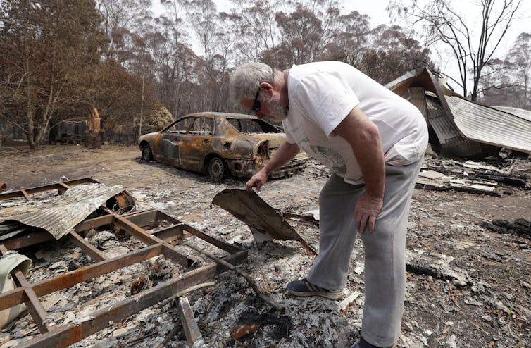 Man inspects debris of his burned house