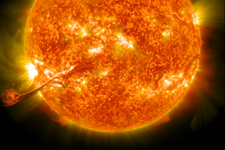 A photo of the Sun with a massive finger of plasma extending from the bottom left into space.