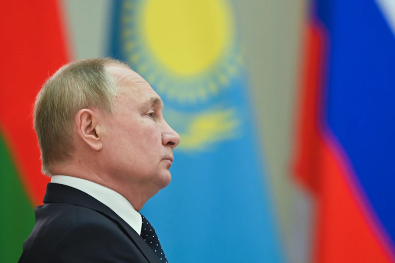 Side profile view of Vladimir Putin with several world flags in the background