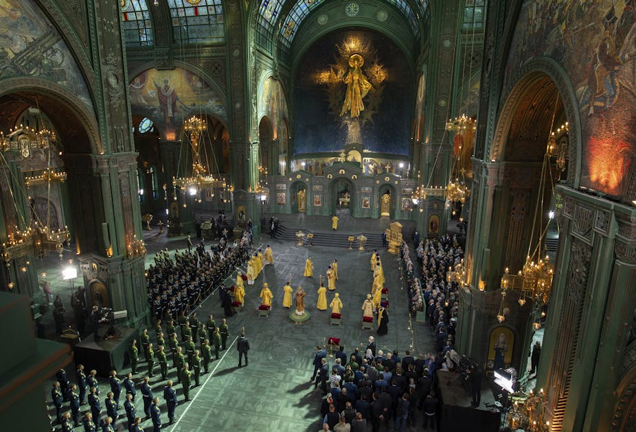 Clergy in yellow robes stand amid worshippers in a cathedral.
