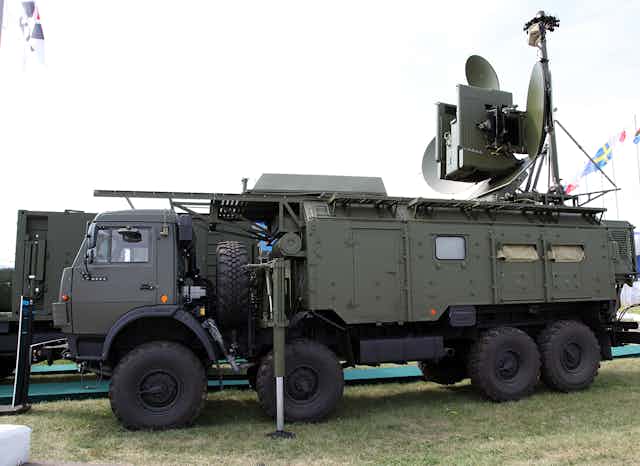a large military vehicle with dish antennas mounted on the roof at the rear