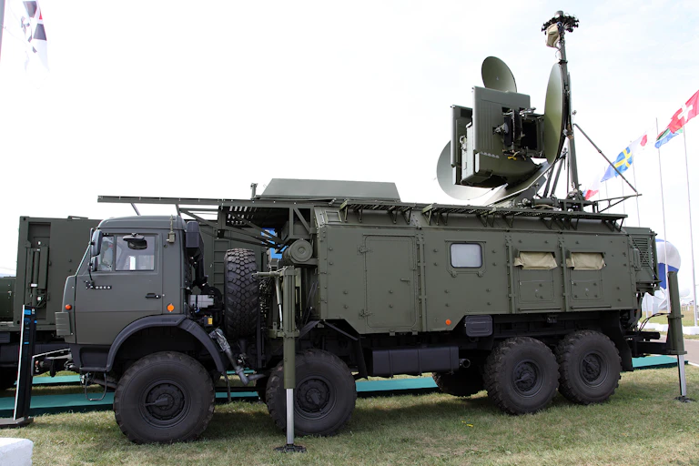 a large military vehicle with dish antennas mounted on the roof at the rear