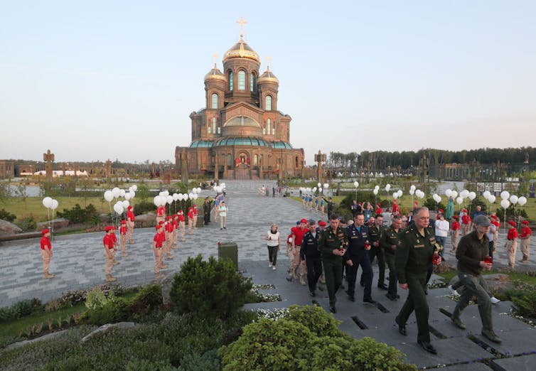 Members of the armed forces walk outside a cathedral in Russia during a ceremony.