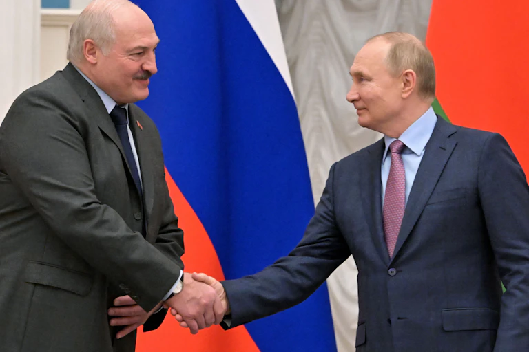 Belarus President Alexander Lukashenko, left, shakes hands with Russian President Vladimir Putin. Behind them stand a Belarus and Russian flag