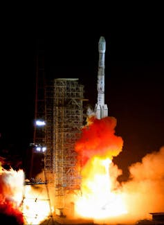 A large white rocket launching in a fiery scene.