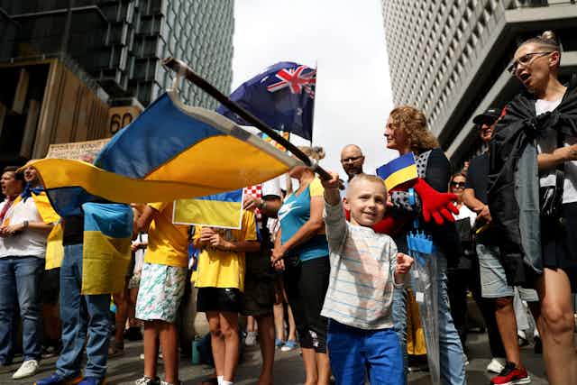 Young boy waves Ukrainian flag at Australian protest.