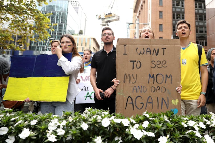 Protestors holding a sign, 'I want to see my Mom and Dad again'.