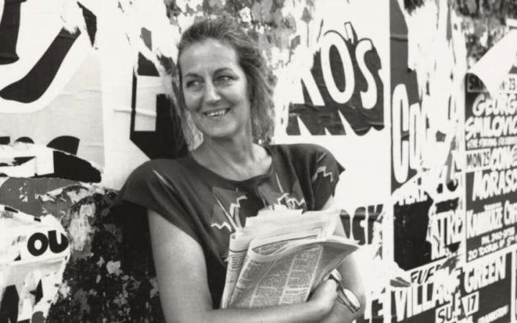 woman smiling, holding newspapers