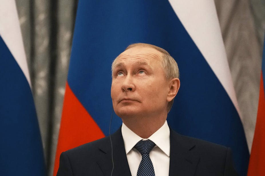 Vladimir Putin in front of Russian flag, looking up