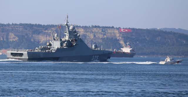 A warship travels through a narrow strait