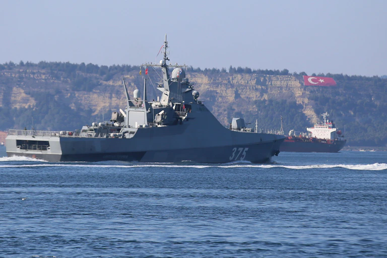 A warship travels through a narrow strait