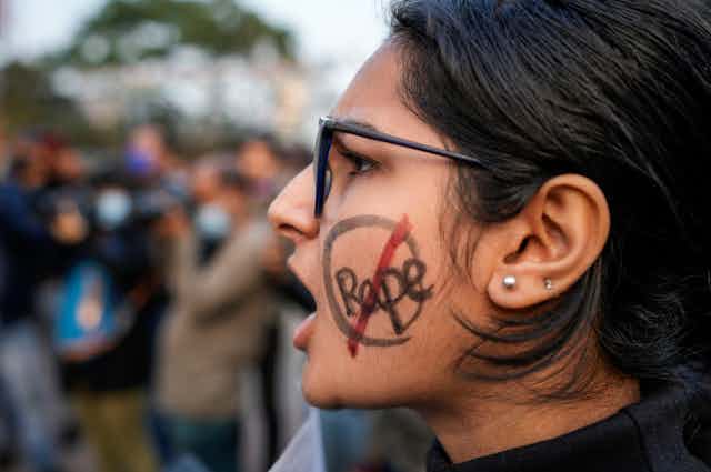 Woman with "rape" written on her cheek and crossed out