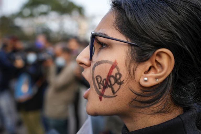 Woman with "rape" written on her cheek and crossed out