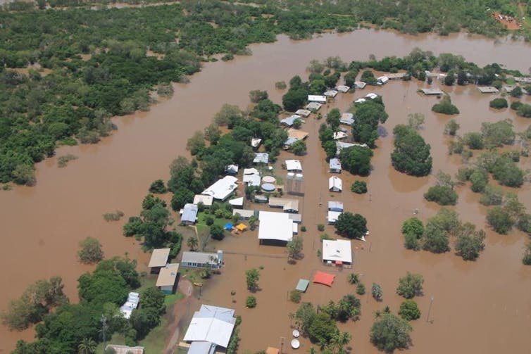 flooded river with trees and roofs of homes