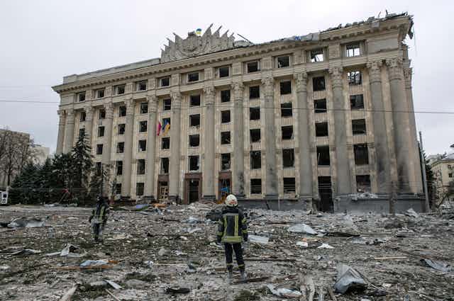 A member of the Ukrainian Emergency Service looks at the City Hall building in the central square following shelling in Kharkiv, Ukraine