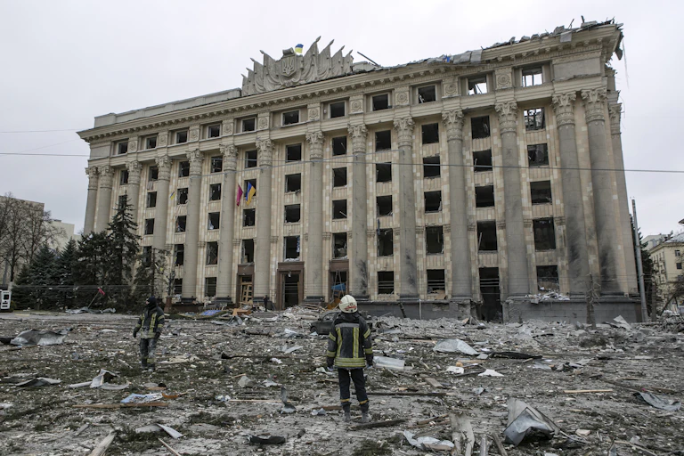 A member of the Ukrainian Emergency Service looks at the City Hall building in the central square following shelling in Kharkiv, Ukraine