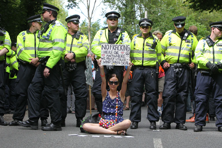 Woman with no fracking placard in front of a line of police