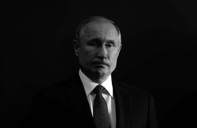 Black and white photo of a frowning Vladimir Putin against a black background