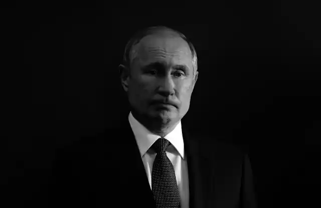 Black and white photo of a frowning Vladimir Putin against a black background