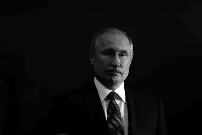 Black and white photo of a frowning Vladimir Putin against a black background