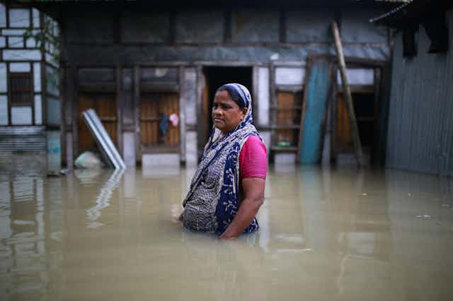 An Indian woman wades through waist-high flood water.