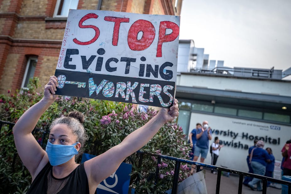 A woman holding up a sign reading "stop evicting key workers"