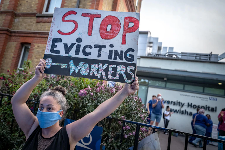 A woman holding up a sign reading "stop evicting key workers"