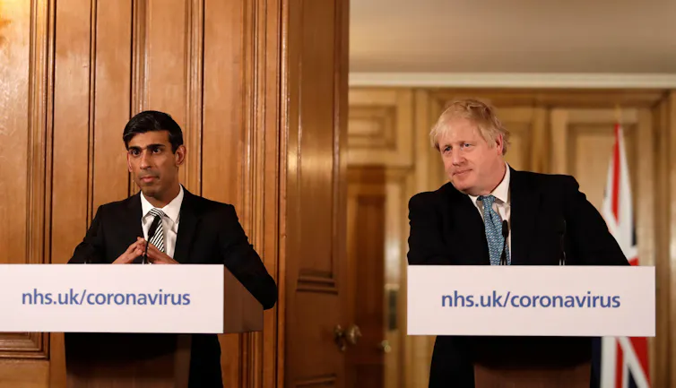Rishi Sunak and Boris Johnson standing at podiums giving a press briefing.