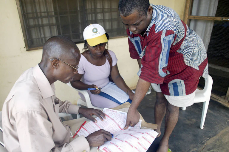 Asaba, NIGERIA: 57 year-old Anthony Odili (R) gives his finger print after census counters (C and L) made the headcount of his family 21 March 2006, in Asaba, Delta State.