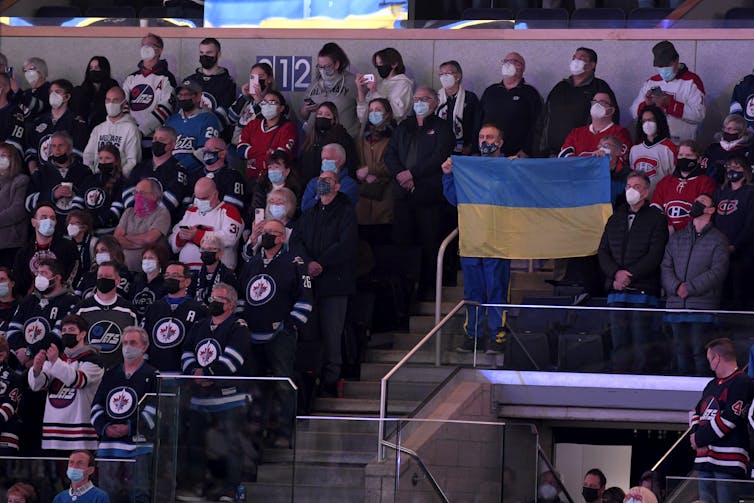 Hockey fans in the stands hold up the Ukrainian flag before an NHL game.