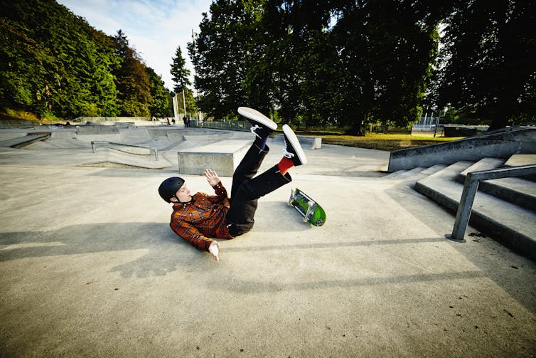 Male skateboarder falling off of railing in skate park .