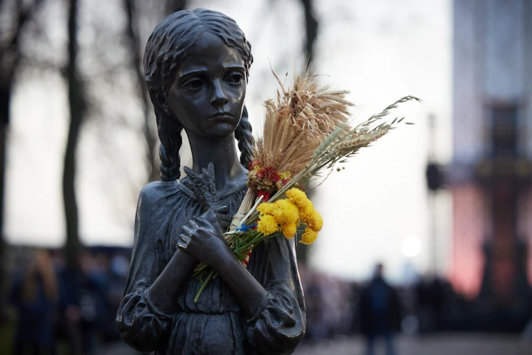 A statue of a girl during the Ukrainian famine, in which someone has placed wheat and flowers.