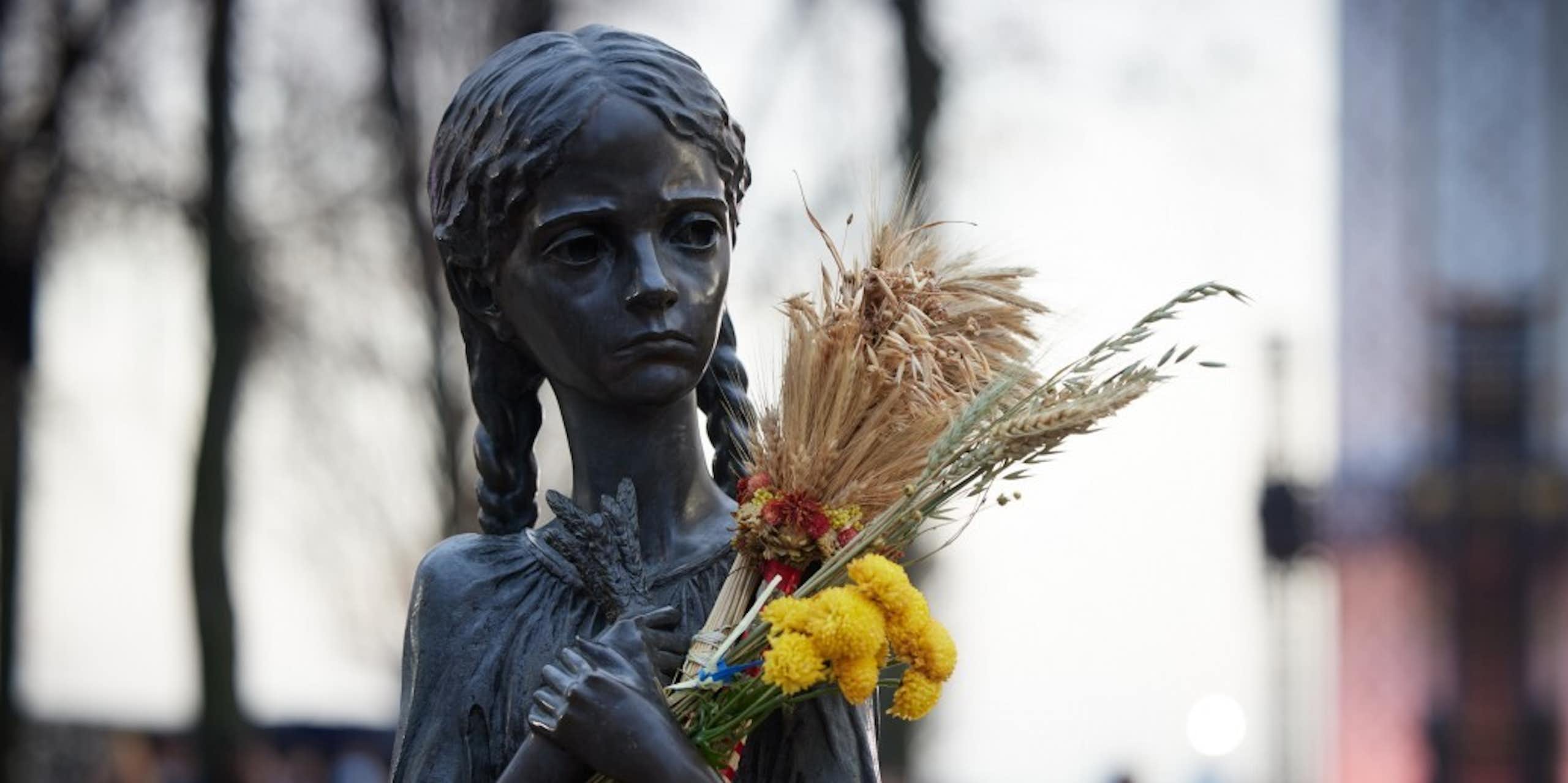 A statue of a girl during the Ukrainian famine, in which someone has placed wheat and flowers.