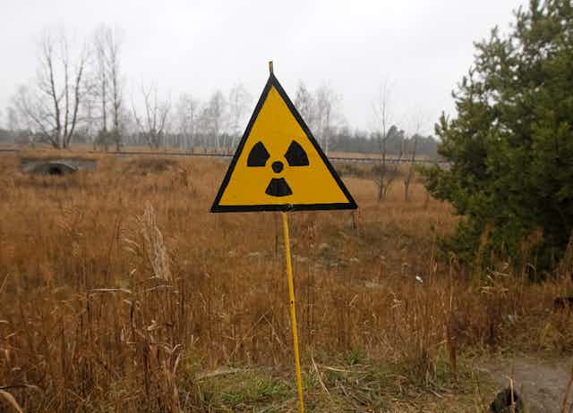 Yellow radiation sign stands at edge of a field