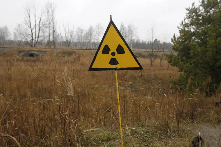Yellow radiation sign stands at edge of a field
